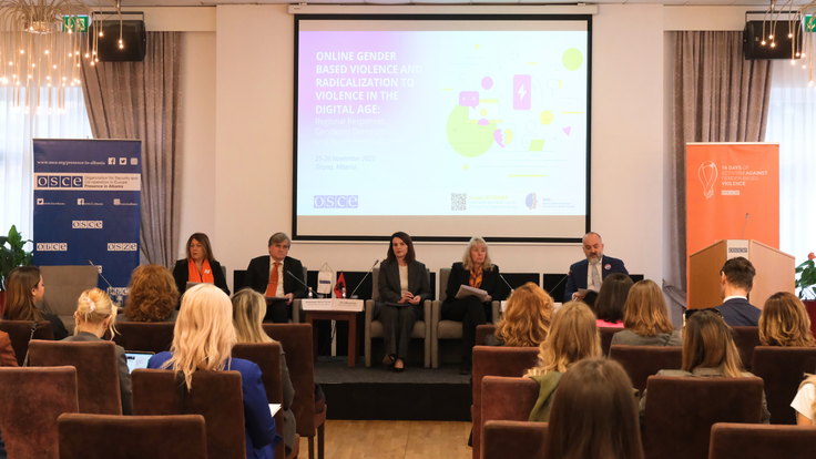 Participants at OSCE event, A panel of five speakers sits on a stage in front of an audience, with an OSCE presentation on gender-based violence displayed on a large screen behind them.