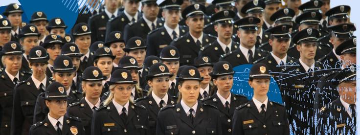 Uniformed officers in black hats standing in formation, focused and attentive.