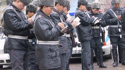 Officers in uniform, wearing fur hats, take notes outside in cold weather.