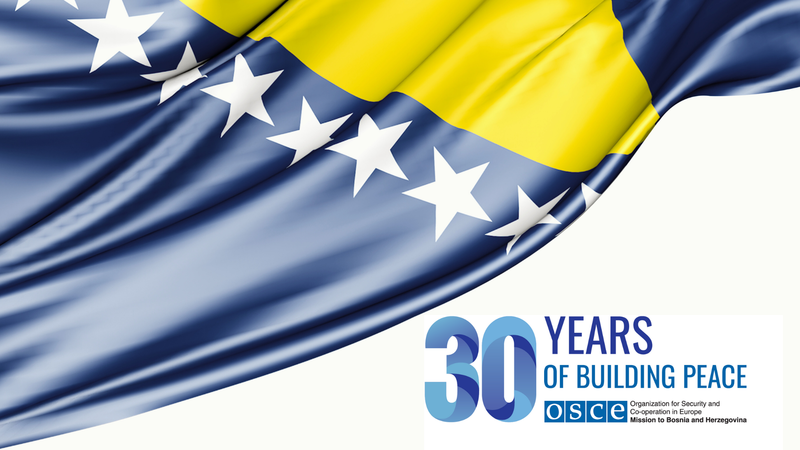 Flag with blue and yellow stripes and stars, text reads "30 Years of Building Peace OSCE."